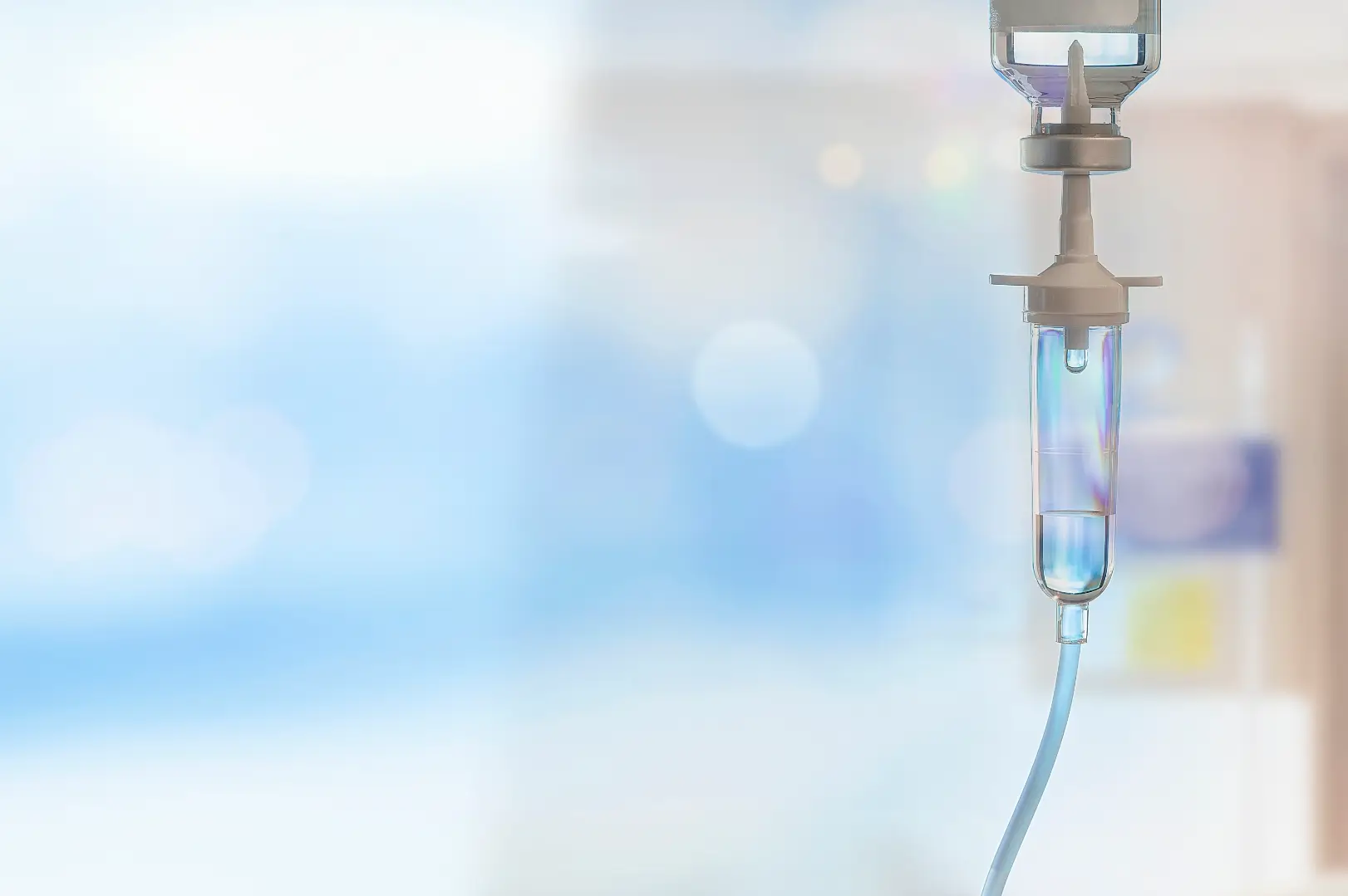 Intravenous IV drip chamber hanging with fluid in a clinical setting.